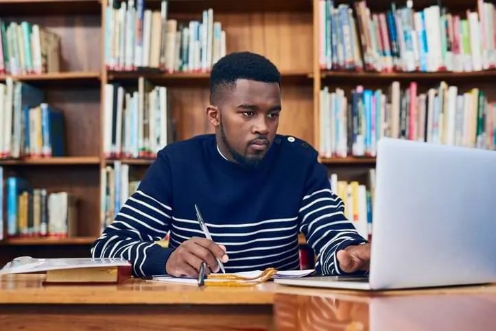 A Man Sitting at a Desk, Focused on his Laptop.