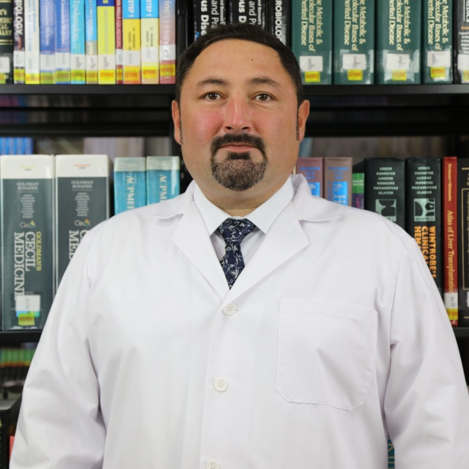 MUA Professor Volodymyr Ikramov standing in the library wearing lab coat.