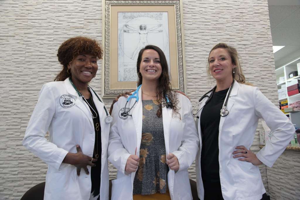 SMU Medical students posing with their white coats during a clinical experience